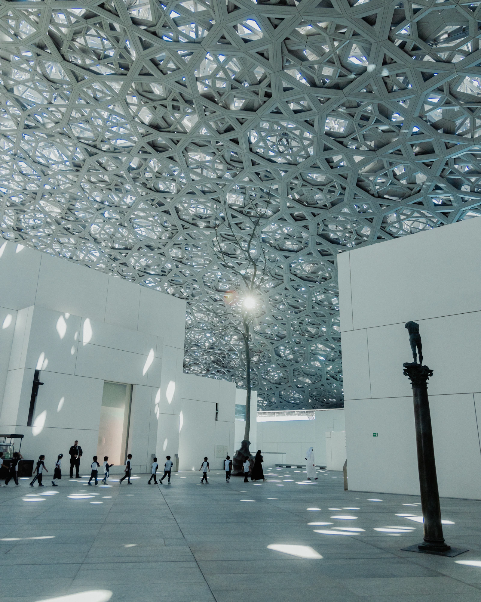 Visitors beneath the lattice dome of Louvre Abu Dhabi