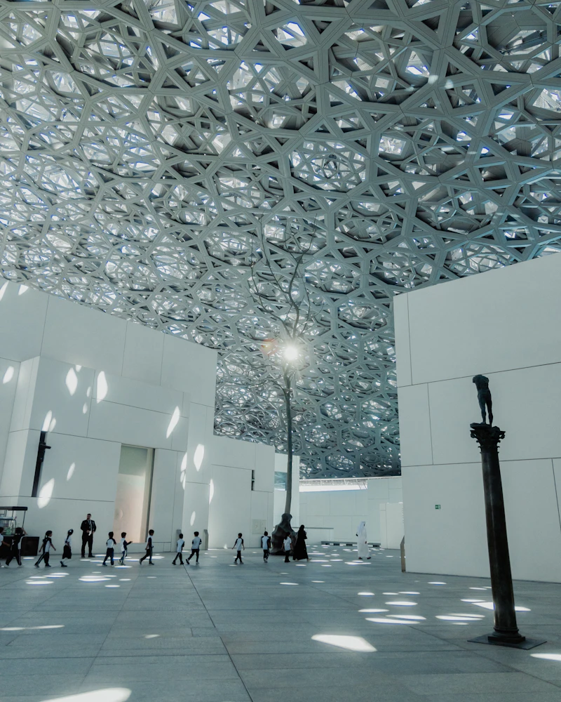 Visitors beneath the lattice dome of Louvre Abu Dhabi