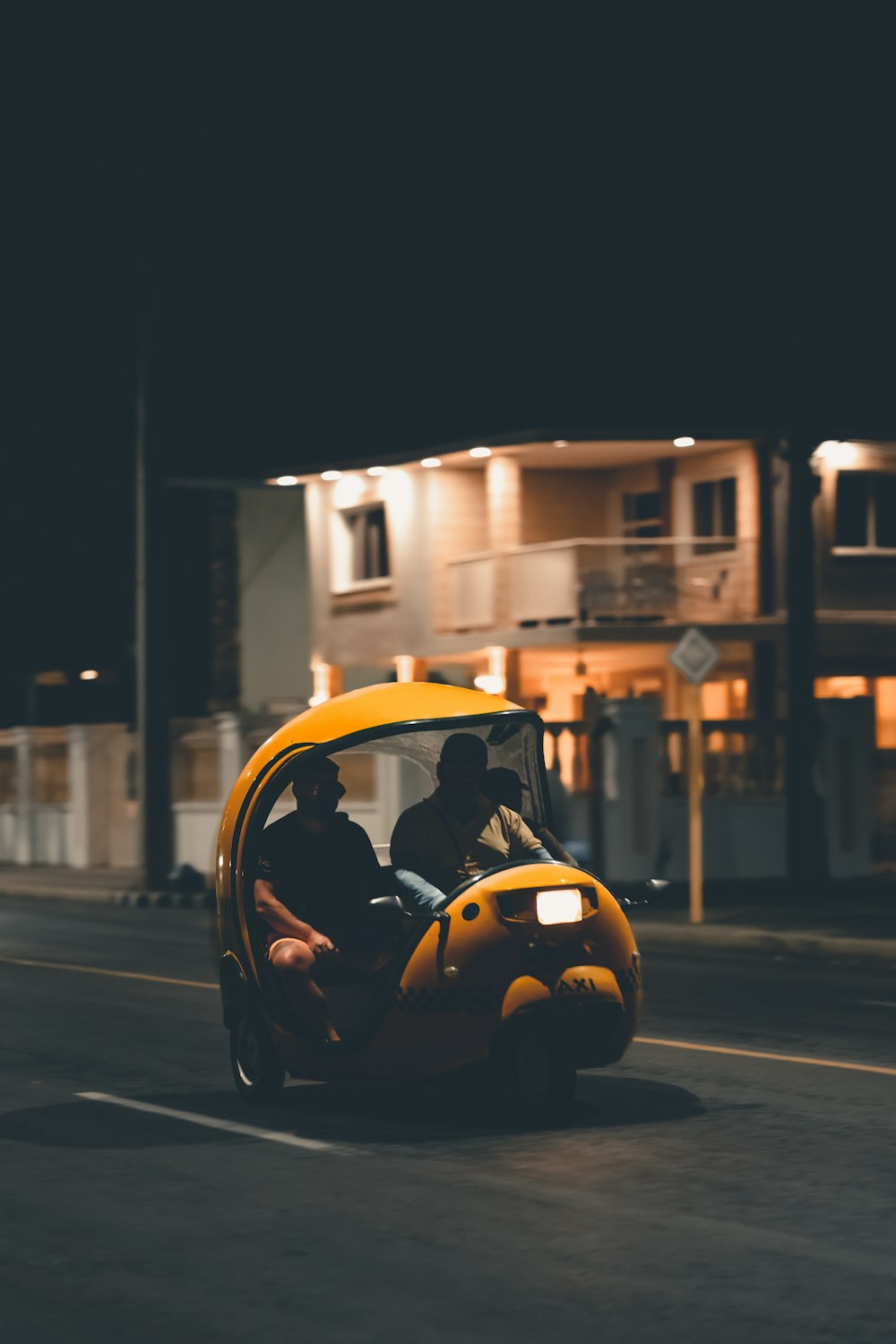 a yellow car driving down a street at night