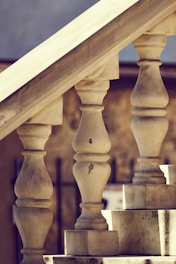 Several stone balusters supporting a staircase, with visible signs of wear and cracks on their surfaces. The image focuses on the architectural details and the texture of the material. The background includes blurred elements, likely more stone or a wall.