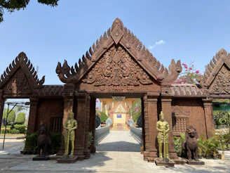 Historic temple entrance framed by blooming flowers and ancient stone carvings.