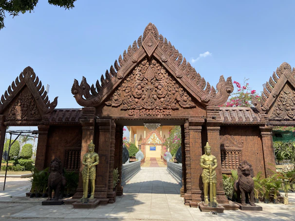 Historic temple entrance framed by blooming flowers and ancient stone carvings.