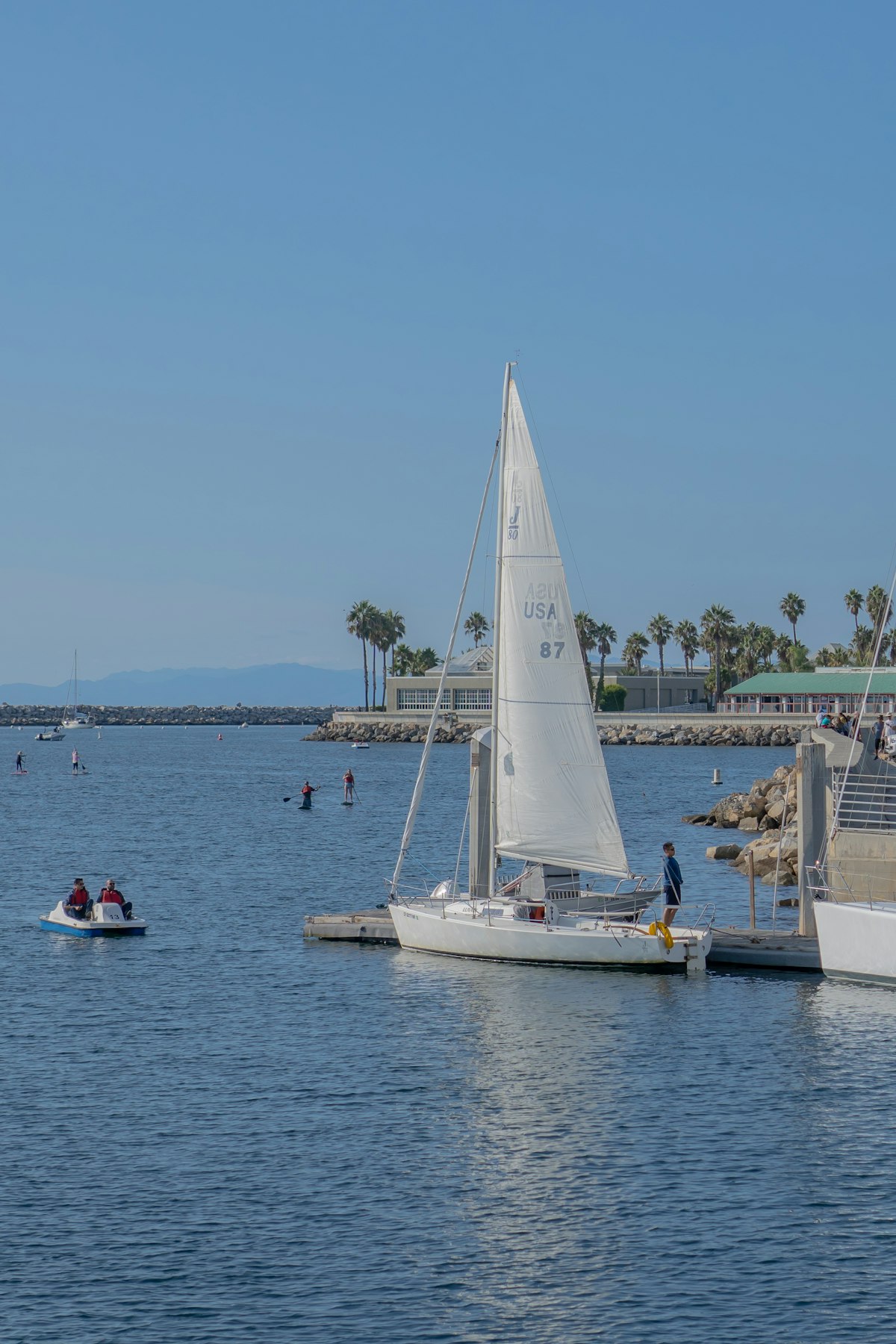 A sailboat on the water near a pier