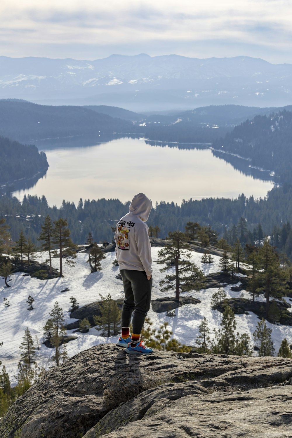 a person standing on top of a mountain overlooking a lake