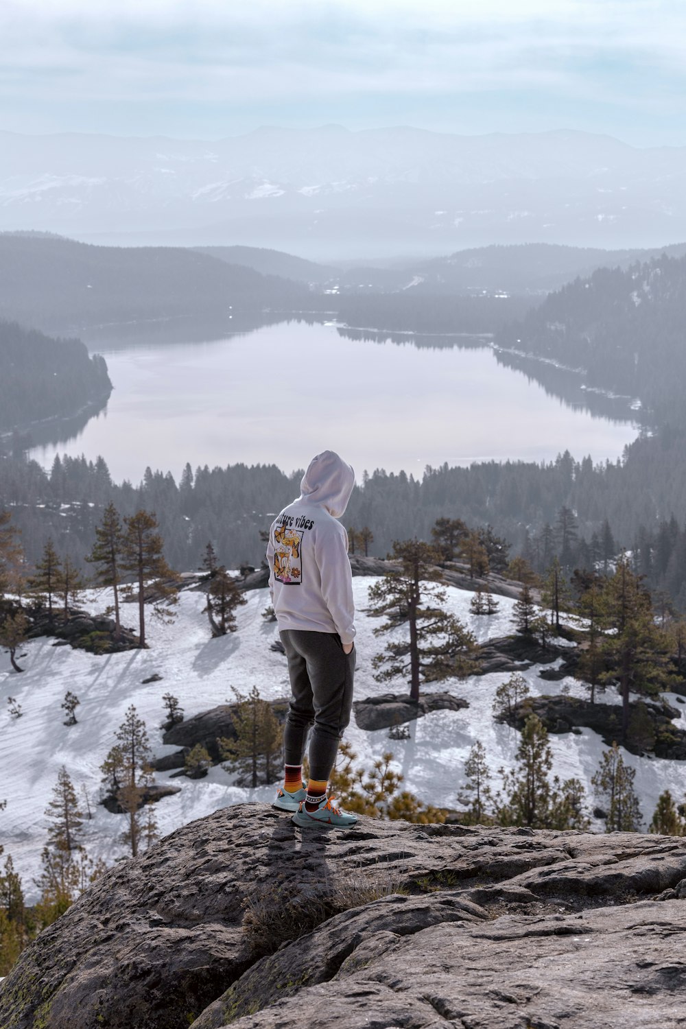 a person standing on top of a mountain overlooking a lake