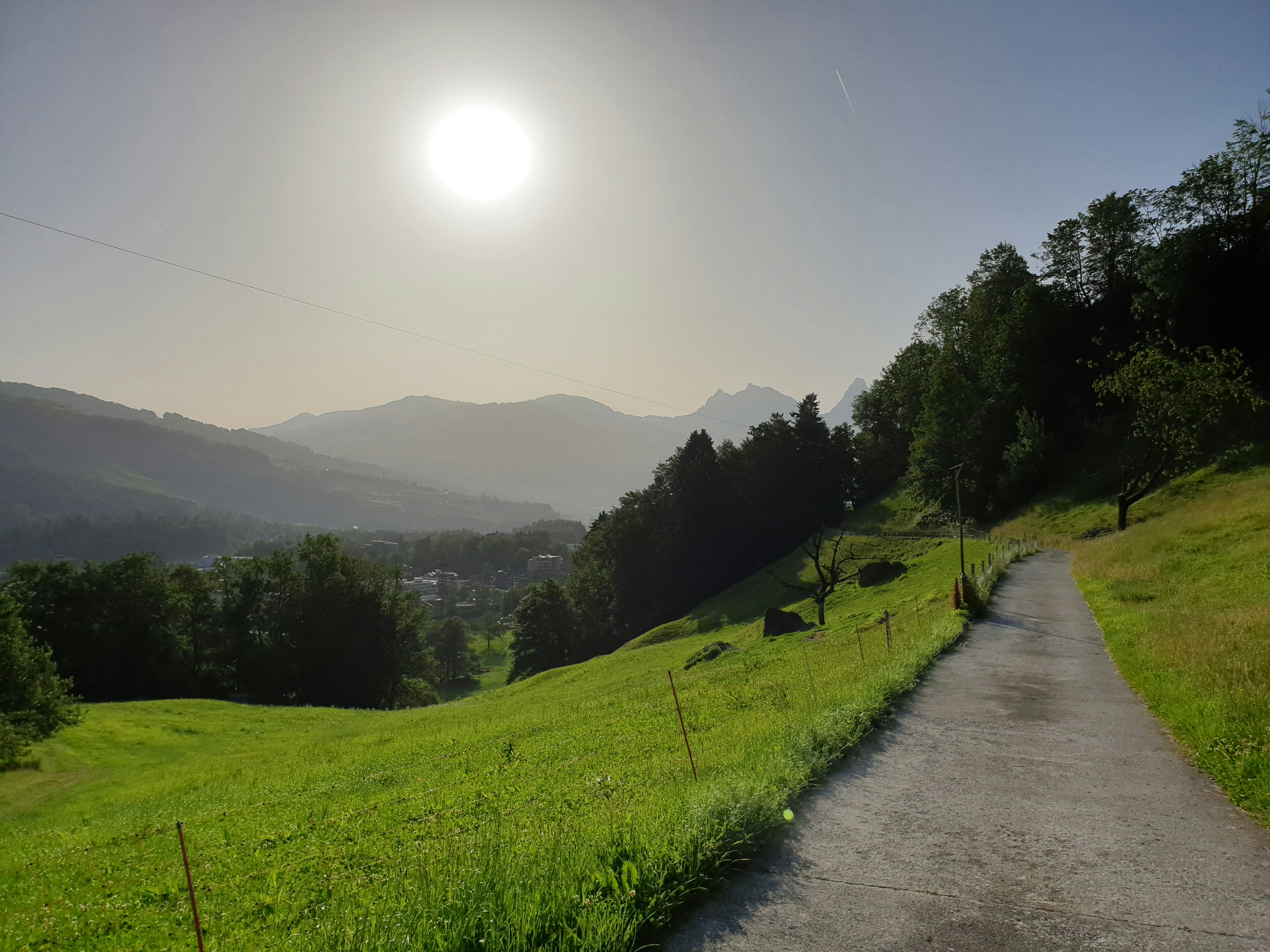 the sun is shining over a grassy hill
