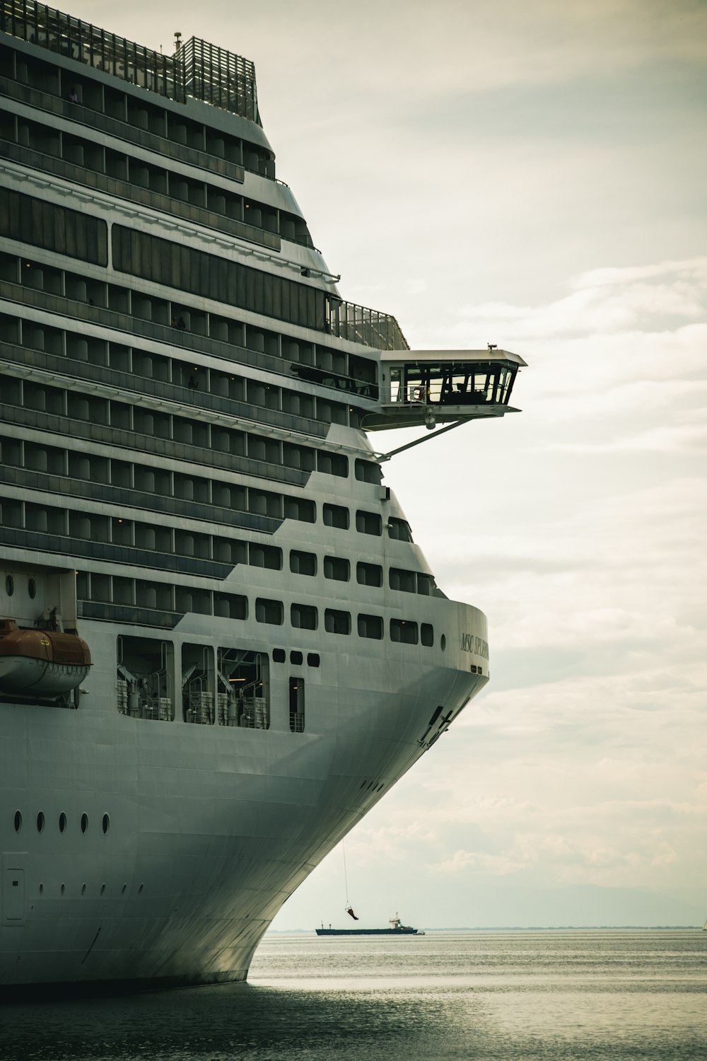 a large cruise ship in the ocean with a small boat in the distance
