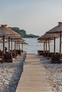 a wooden walkway leading to a beach with umbrellas
