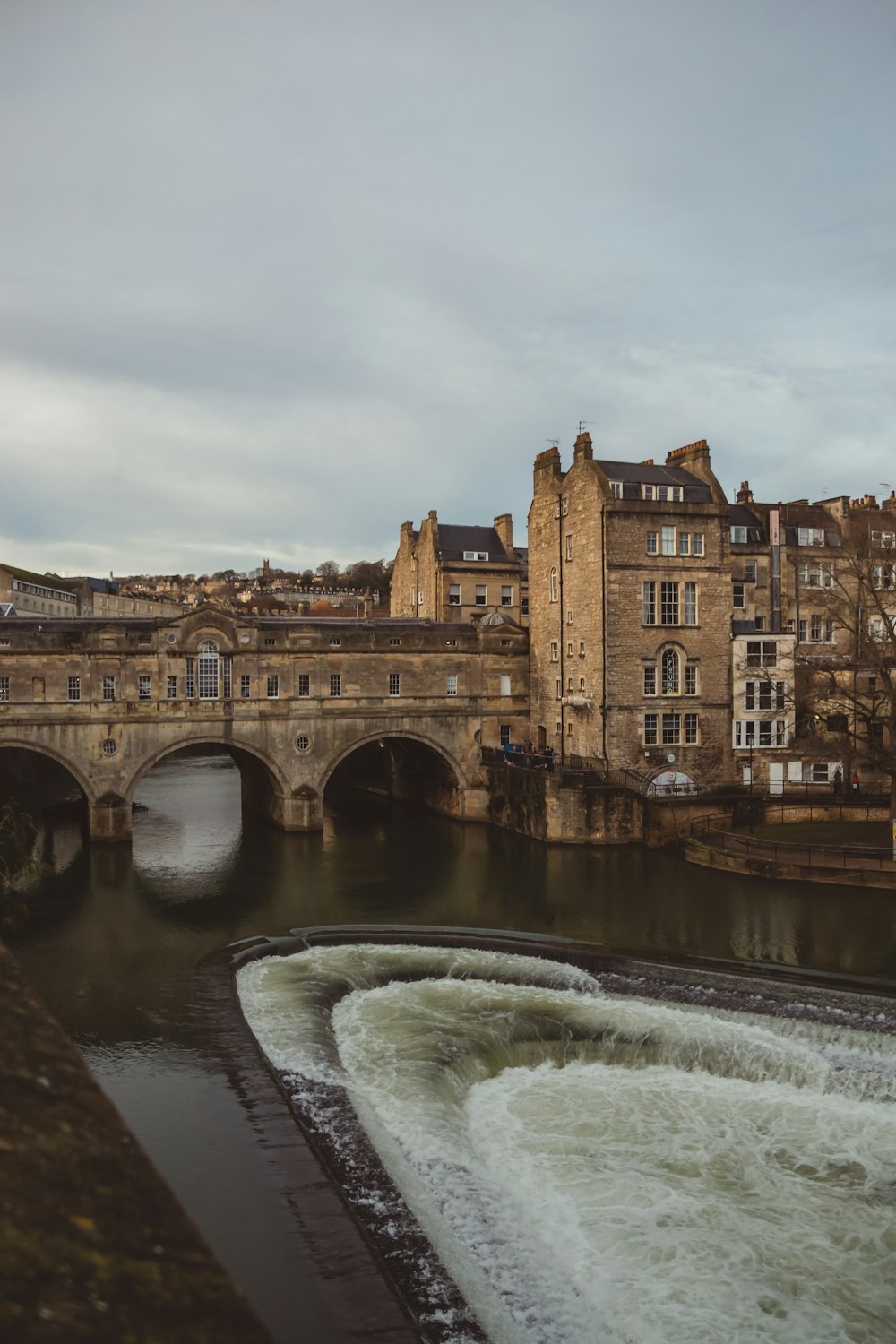 a river flowing under a bridge next to a tall building