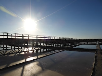 the sun is shining over a bridge over a body of water