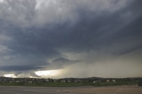 A dramatic hailstorm with dark clouds and hailstones falling over a suburban street.