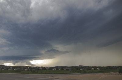 A dramatic hailstorm with dark clouds and hailstones falling over a suburban street.