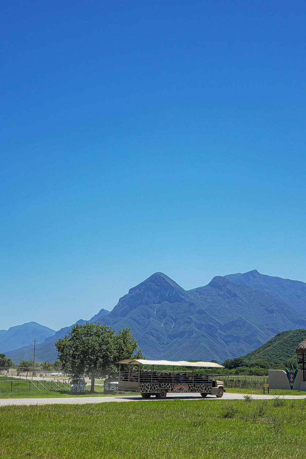 a bus parked in a field with mountains in the background