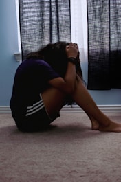 a woman sitting on the floor with her head in her hands