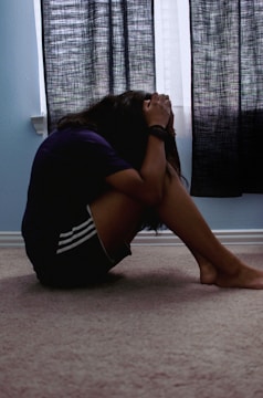 a woman sitting on the floor with her head in her hands