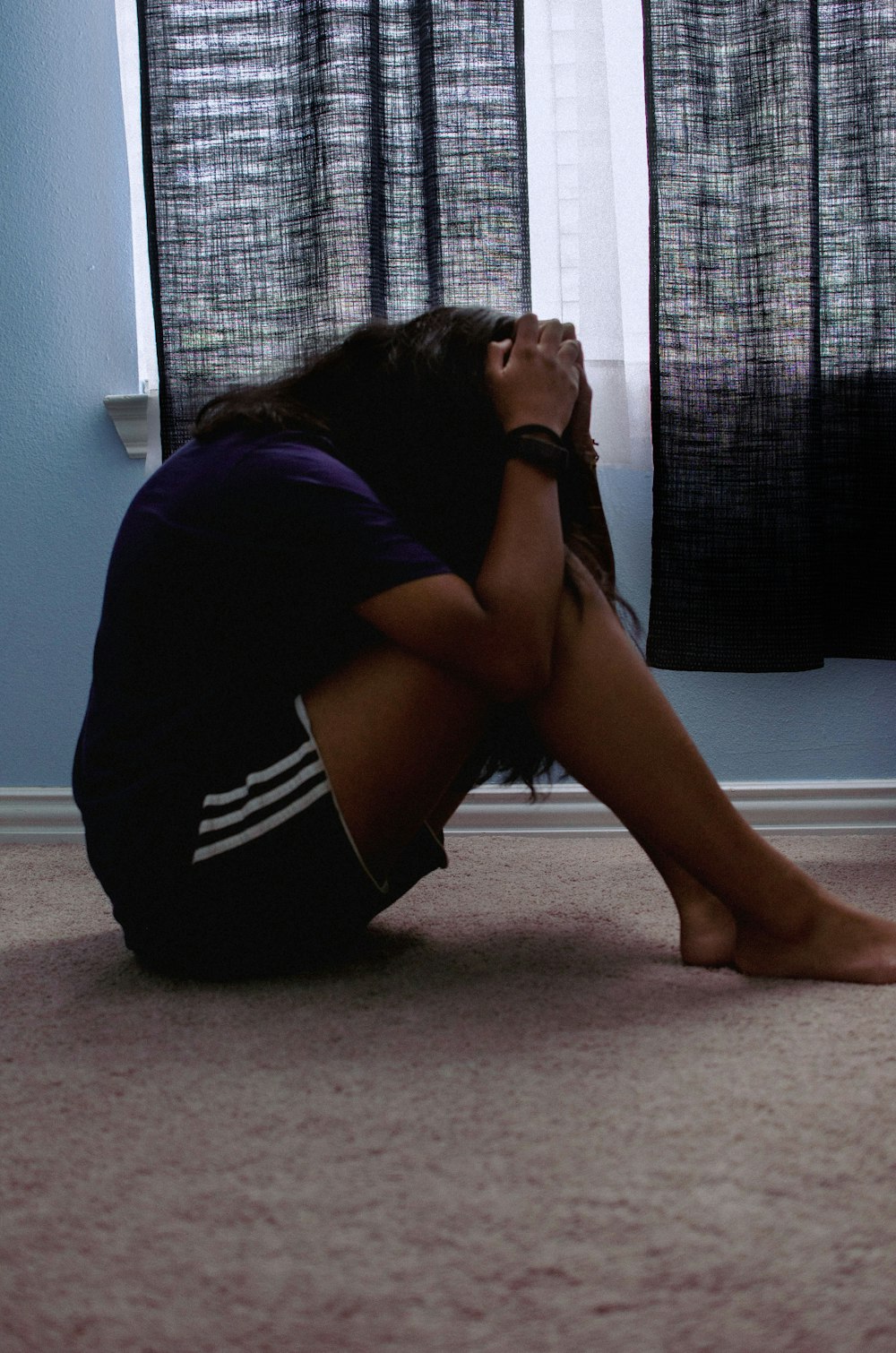 a woman sitting on the floor with her head in her hands