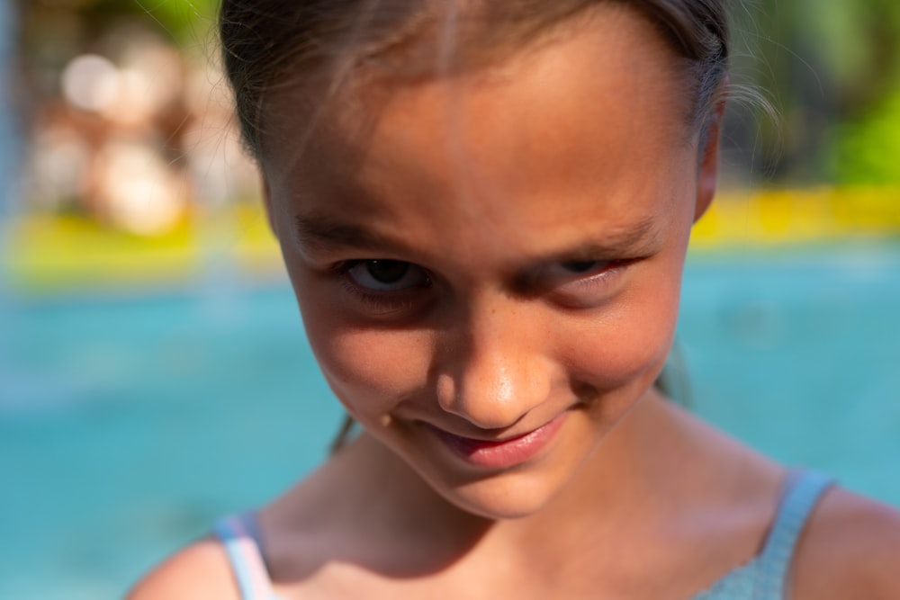 a little girl standing in front of a swimming pool