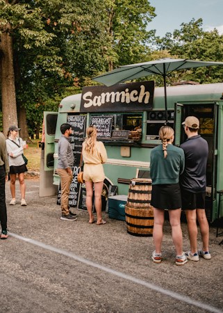 A group of people lined up outside a food truck at an outdoor festival, similar to the setup at the Great American Foodie Fest in Henderson
