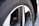 A close-up view of a car wheel with a five-spoke alloy rim and a tire. The tire's tread pattern and sidewall text are visible, including the brand name.