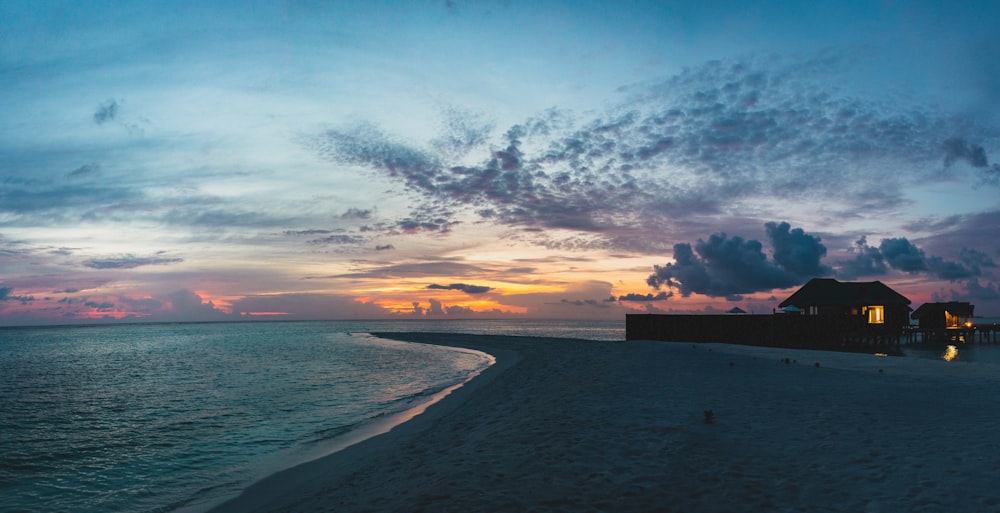 a house on a beach with a sunset in the background