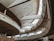 A modern architectural interior with large, sweeping concrete curves and expansive high windows allowing natural light to flood the space. The design features multiple levels and a spacious open layout, creating an airy and dynamic atmosphere.