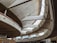 A modern architectural interior with large, sweeping concrete curves and expansive high windows allowing natural light to flood the space. The design features multiple levels and a spacious open layout, creating an airy and dynamic atmosphere.
