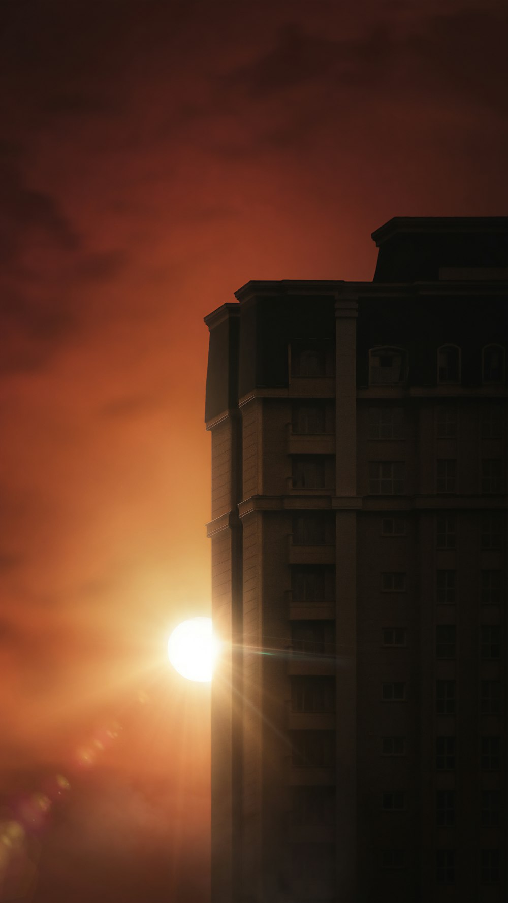 the sun is setting behind a tall building