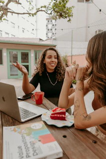 Two women sitting at a table with a laptop