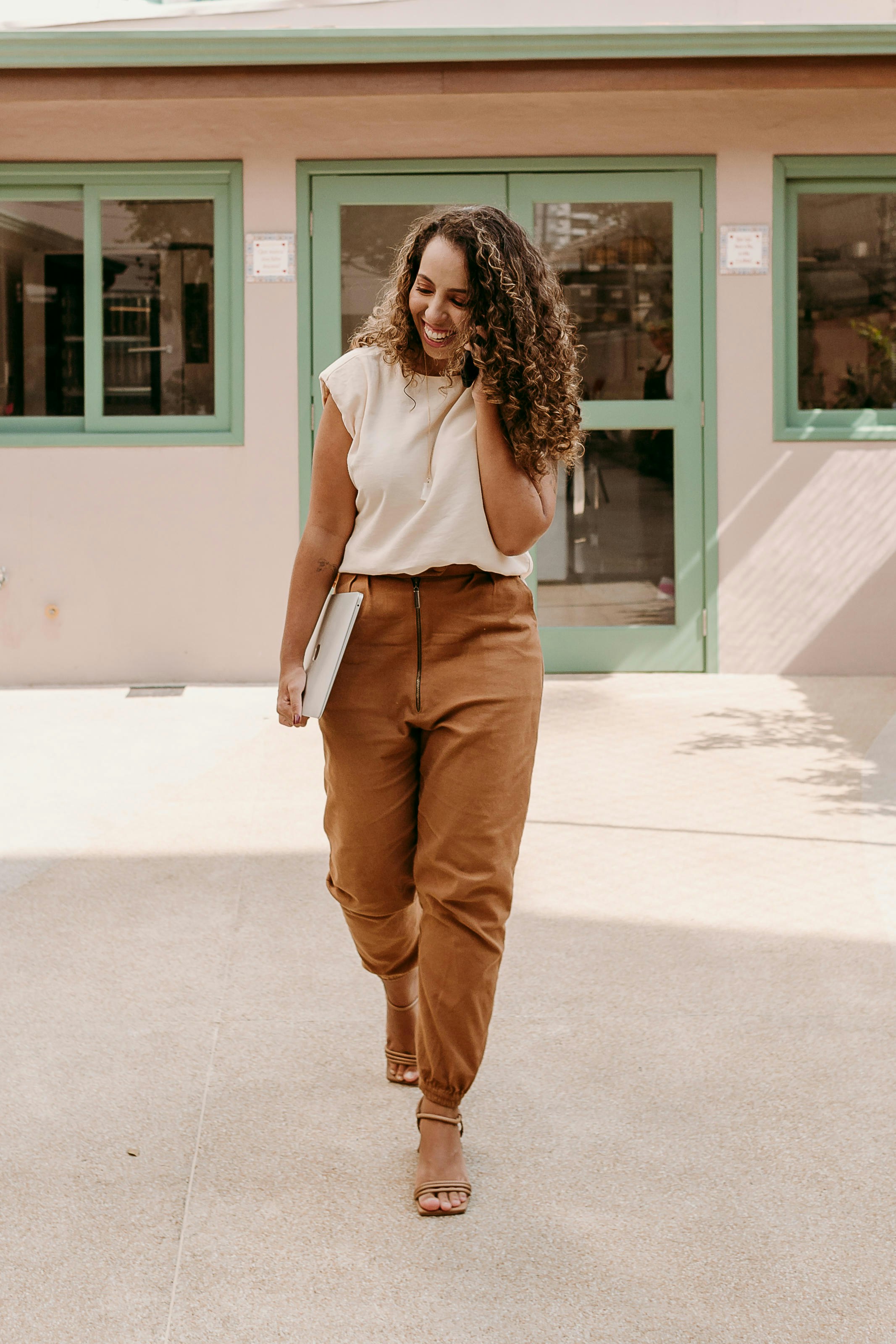 A woman walking down a sidewalk talking on a cell phone