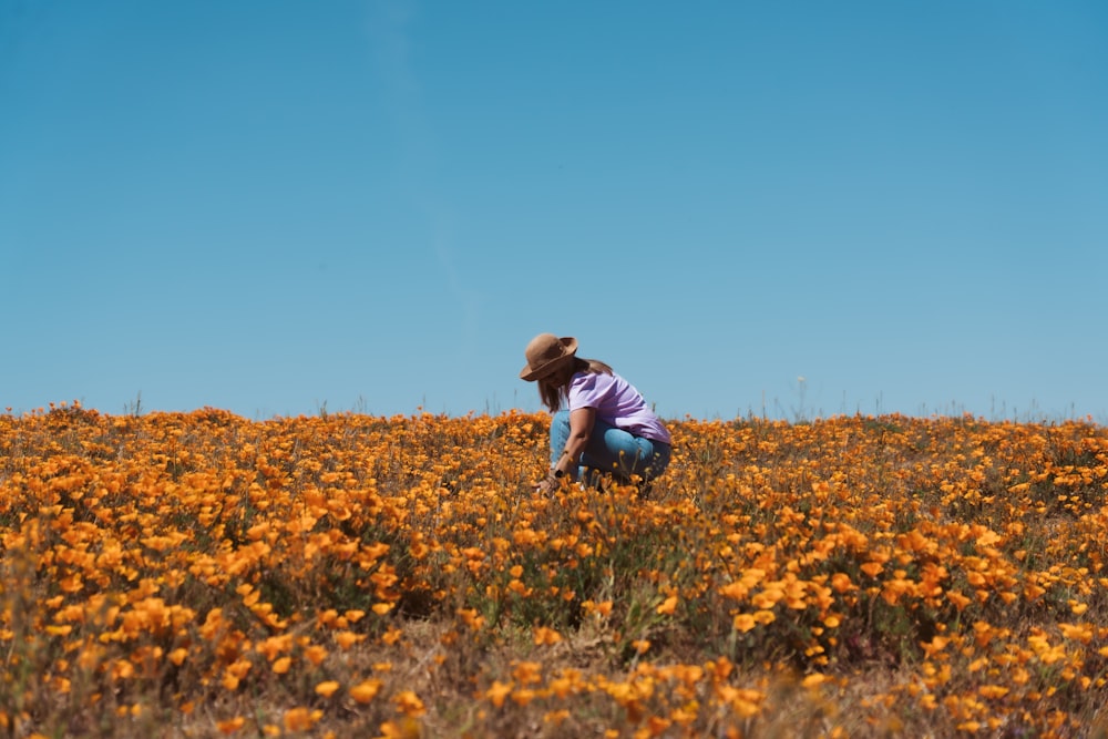 a person kneeling down in a field of flowers