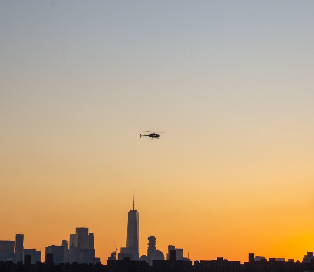 Un hélicoptère survolant une ville au coucher du soleil