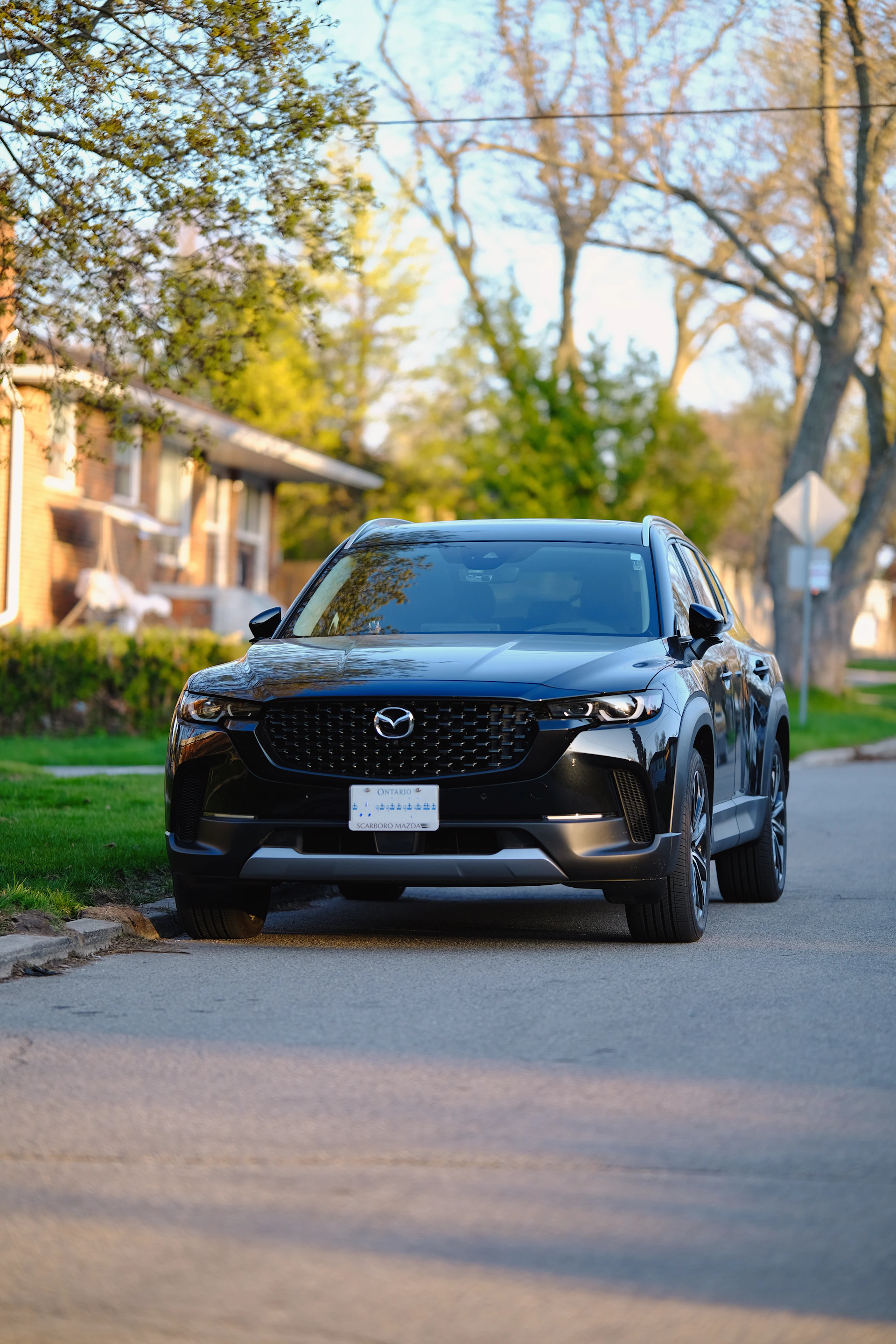 Sleek graphite-colored SUV gleaming after a meticulous exterior detail, parked on a quiet suburban street.