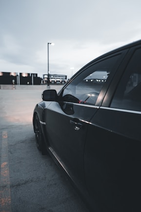 A sleek black car being carefully loaded onto a transport truck at dusk.