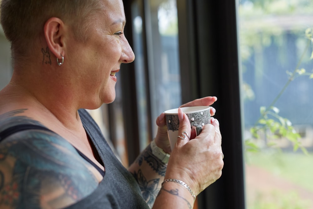 a woman holding a cup of coffee looking out a window