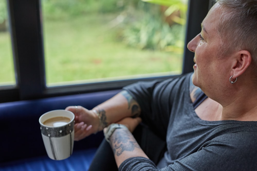 a man holding a cup of coffee looking out a window