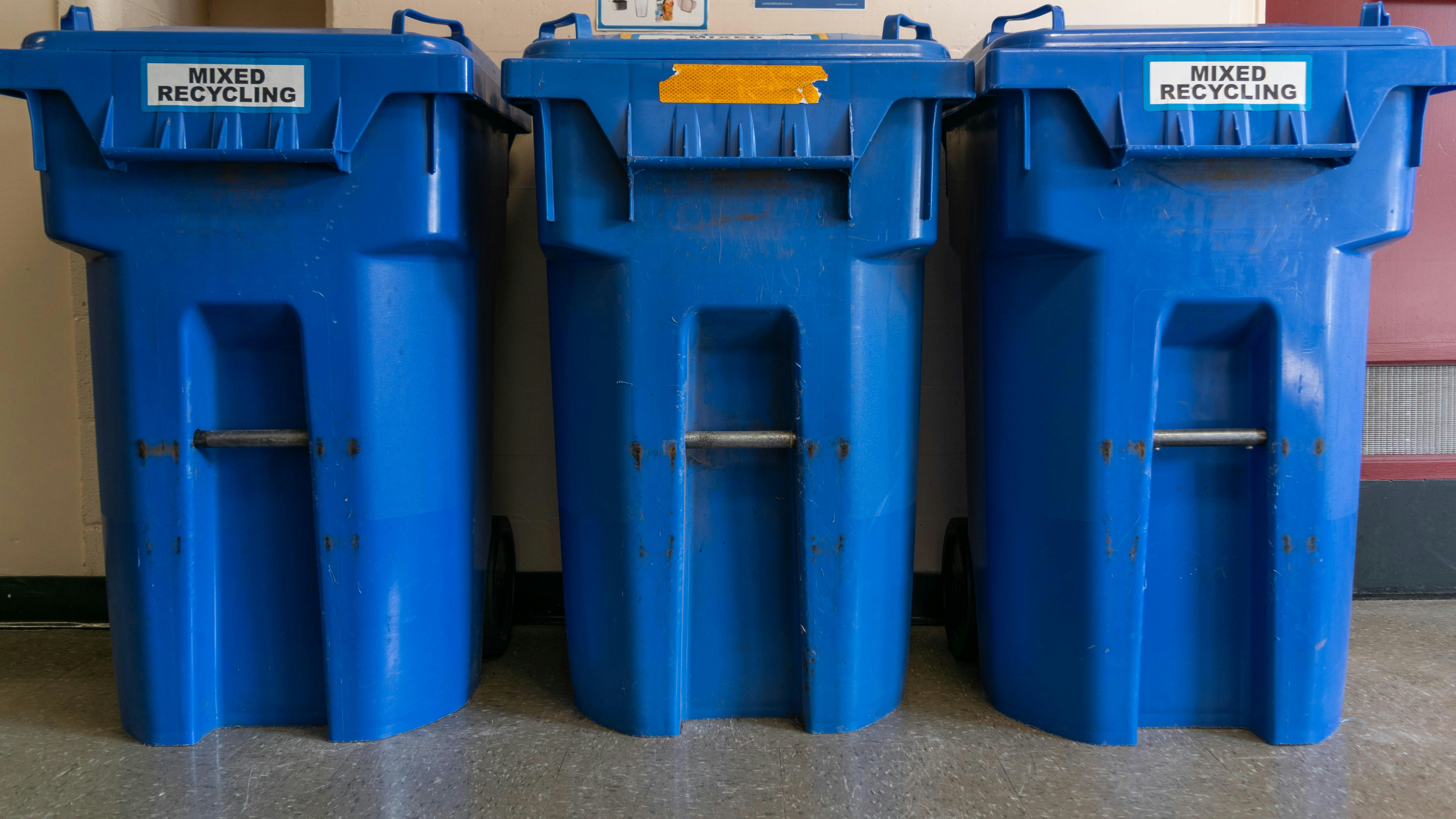 a couple of blue trash cans sitting next to each other