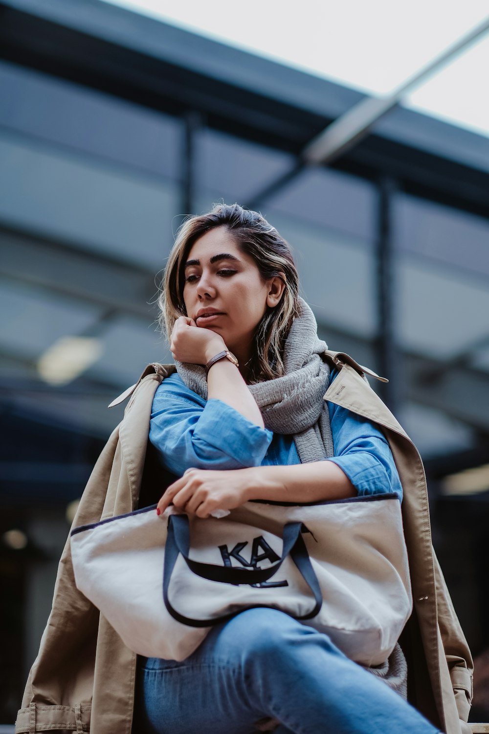 a woman sitting on a bench with her hand on her chin