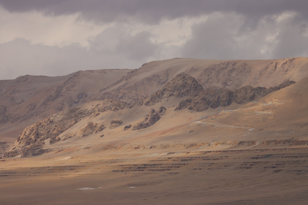 a mountain range in the desert under a cloudy sky