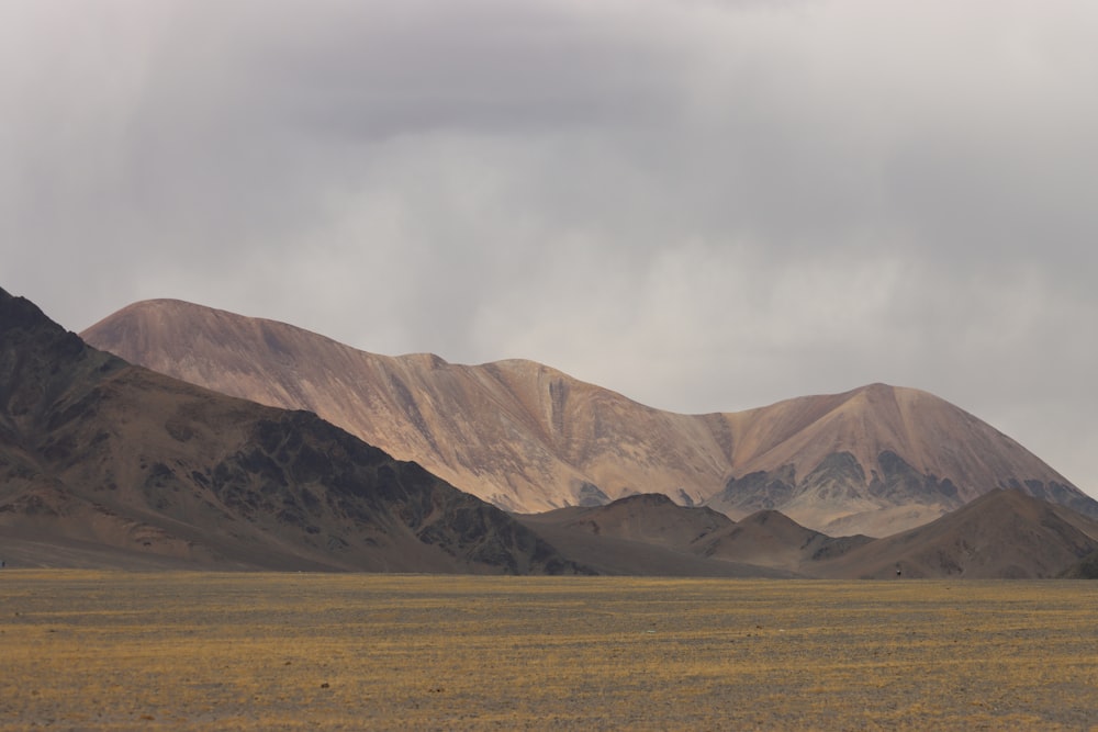 a mountain range in the desert under a cloudy sky