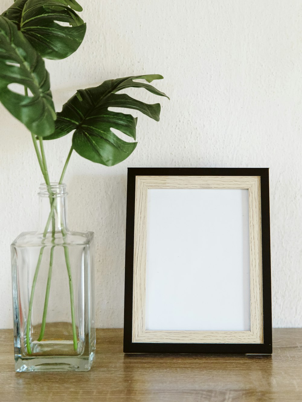 a plant in a vase next to a picture frame