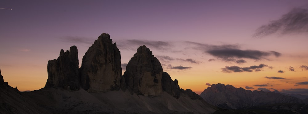 a group of tall mountains sitting under a purple sky