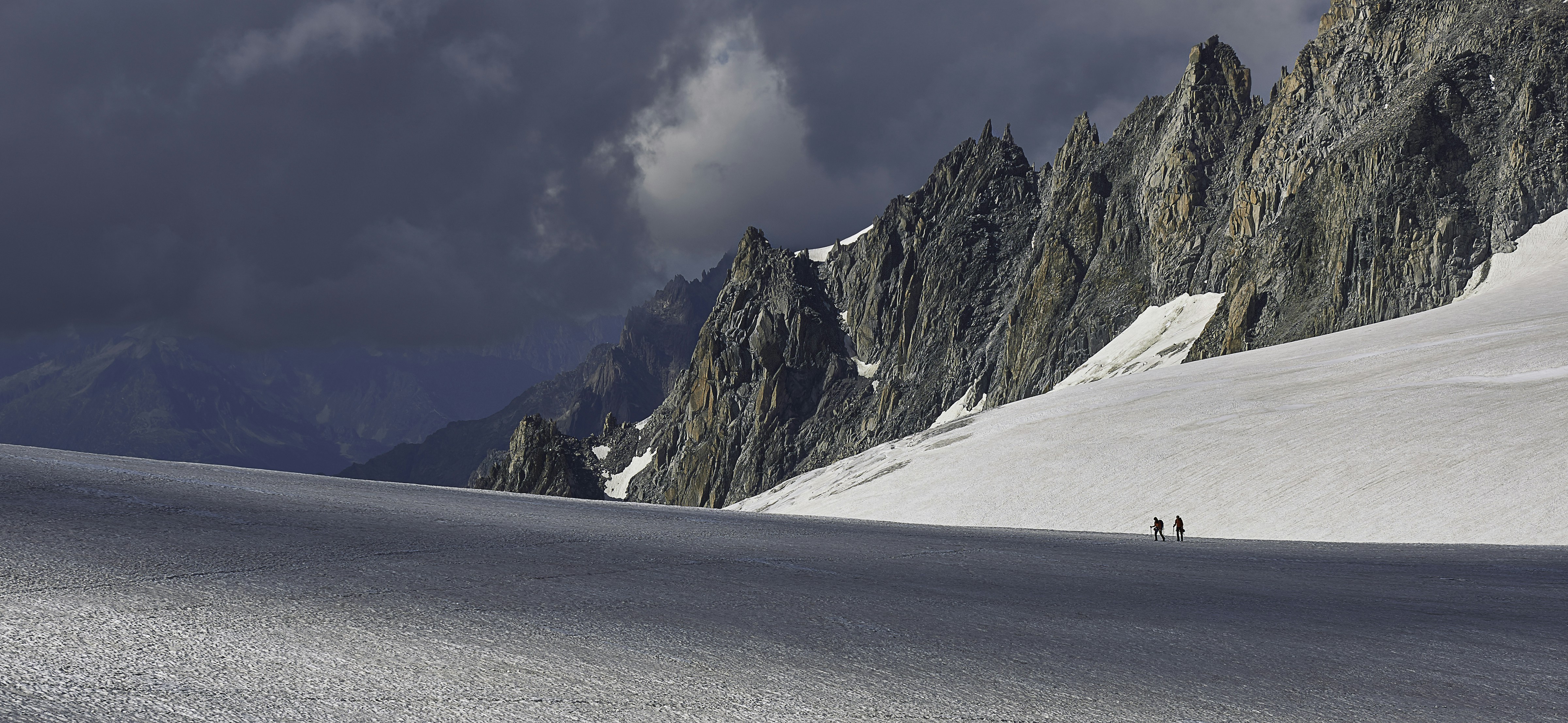a couple of people riding skis down a snow covered slope