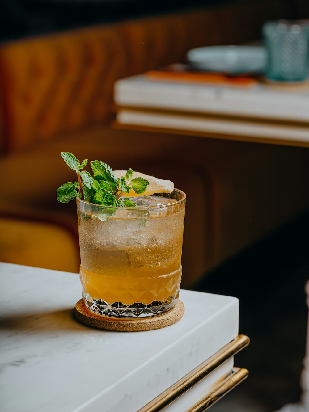 a tall glass with a mint garnish sits on a table