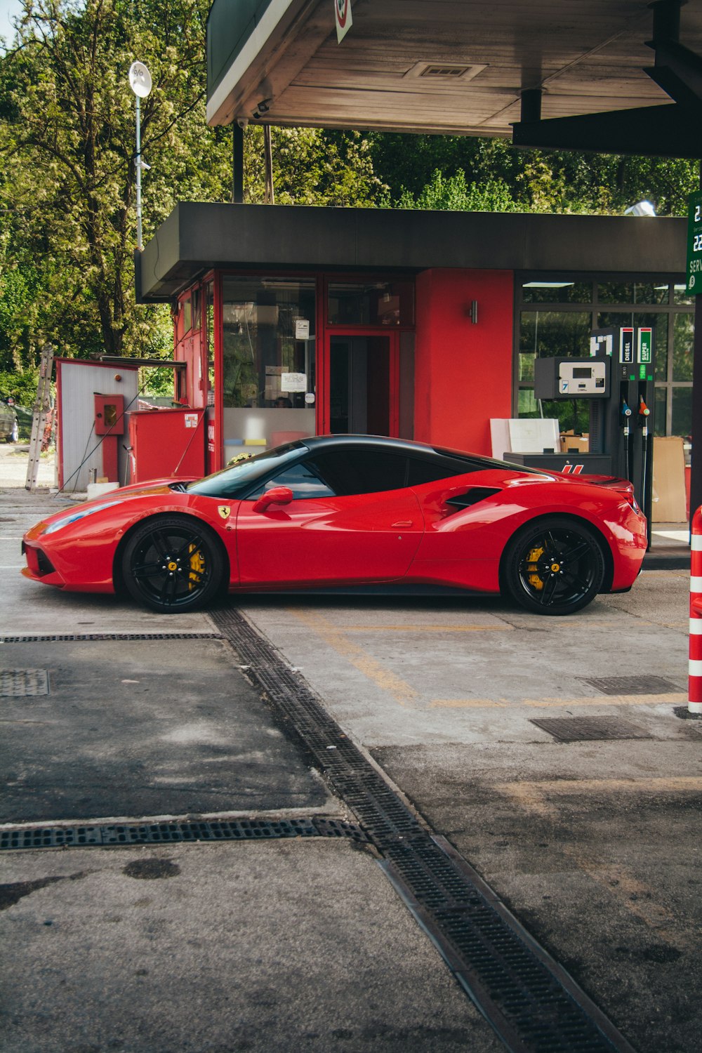 um carro esportivo vermelho estacionado em frente a um posto de gasolina