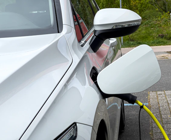 A yellow electric car charging at a stylish Eigenstroom branded charging station outside a cozy home.
