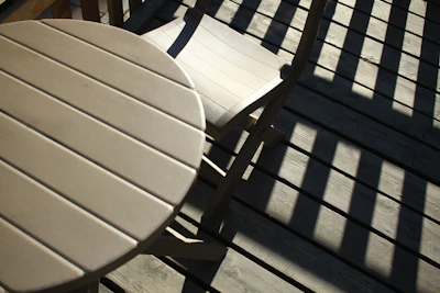Outdoor aluminum dining chair set under dappled sunlight on a wooden deck.