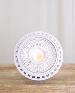 A close-up of a modern LED spotlight illuminating a dark background.