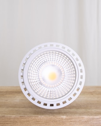 A bright LED light bulb on a wooden table.
