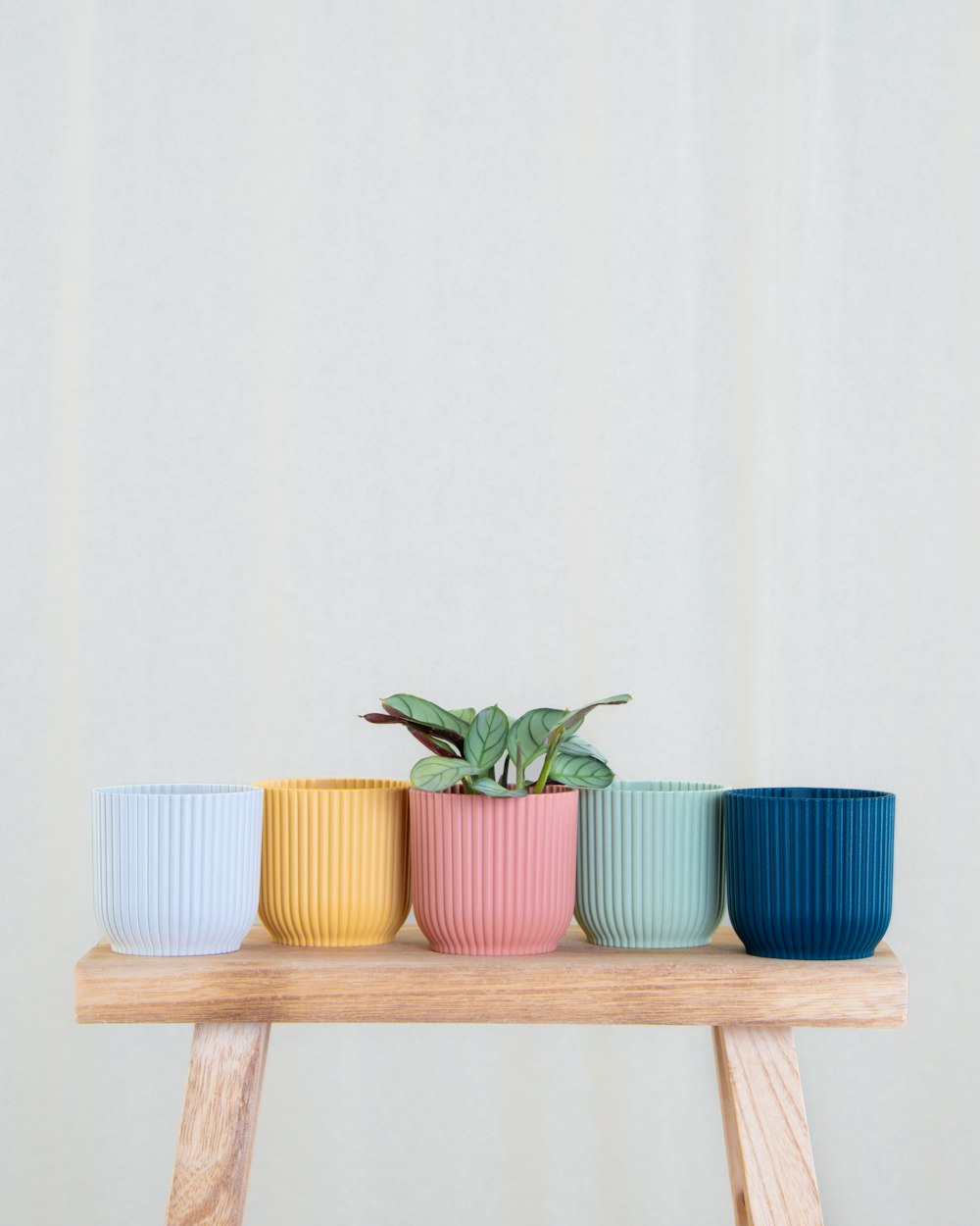 a wooden table topped with four different colored cups