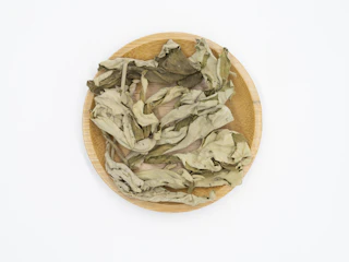 Soursop leaves freshly picked, laid out on a woven mat.